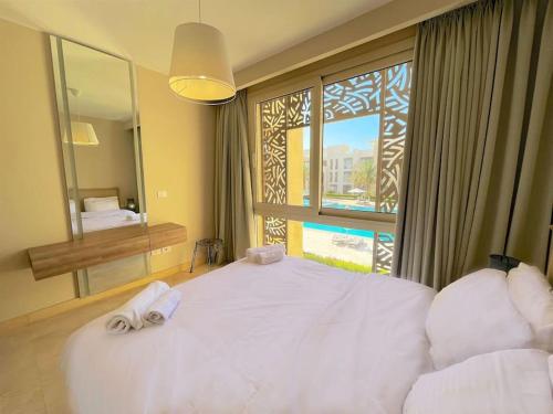 een slaapkamer met een groot wit bed en een raam bij Stunning 2 BR/ Free Beach & Pool Access @ Mangroovy, El Gouna in Hurghada
