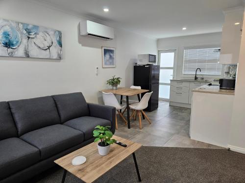 a living room with a couch and a table and a kitchen at Redwood Apartments in Rotorua