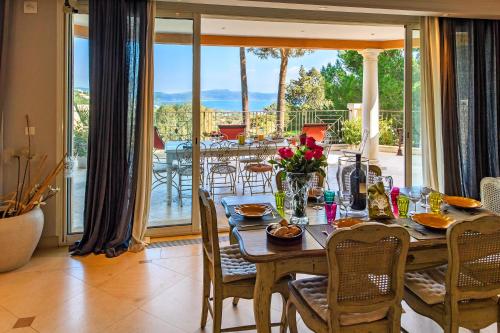 une salle à manger avec une table et un balcon dans l'établissement Villa Darius Belle et grande villa, piscine, clim, vue mer Cavalaire sur Mer, à Cavalaire-sur-Mer