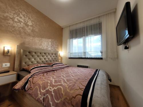 a bedroom with a bed and a television on a wall at Apartman Lux Titova Vila Plus Sony PS in Zlatibor
