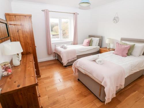 a bedroom with two beds and a table and a window at Egret in Milford Haven