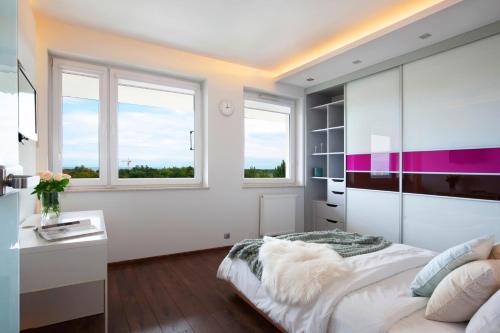 a bedroom with a bed and a desk and windows at Elite Apartments Seaview Tower in Gdańsk