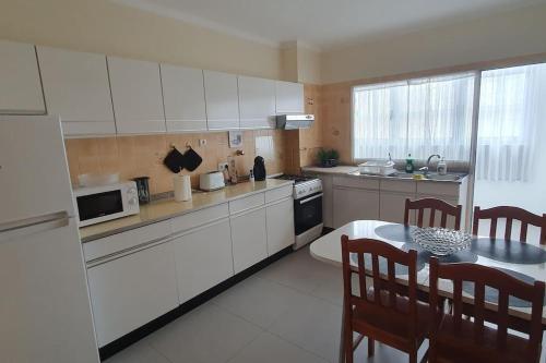 eine Küche mit weißen Schränken und einem Tisch und Stühlen in der Unterkunft Appartement de 90 m2 en 1ere ligne face a l'ocean in Vila Praia de Âncora