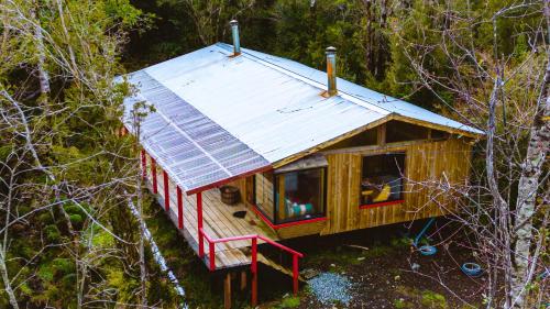 una piccola casa con un tetto di metallo nel bosco di Cabañas Tierra Hermosa a Hornopiren