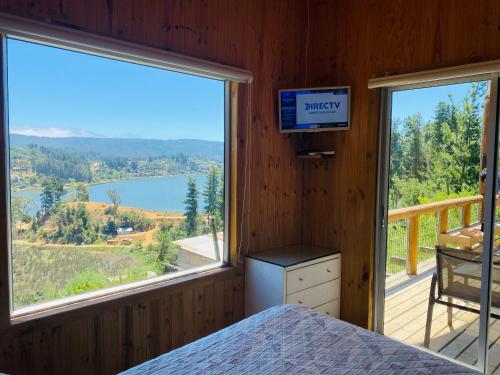 1 dormitorio con cama y vistas al lago en Cabaña La Puntilla, en Vichuquén