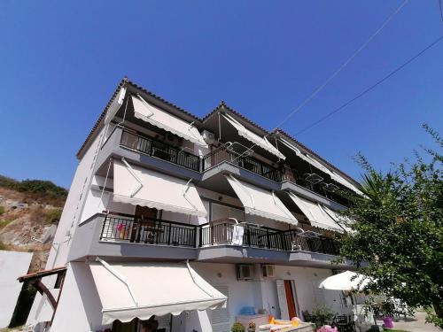 a large white building with balconies and umbrellas at House Stella Kalamitsi - Studios & Apartments in Kalamitsi