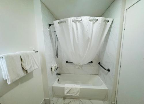 a white bathroom with a tub and a shower curtain at Ramada by Wyndham San Diego Airport in San Diego