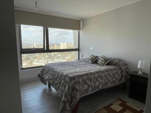 1 dormitorio con cama y ventana grande en departamento con vista al mar, en Concón