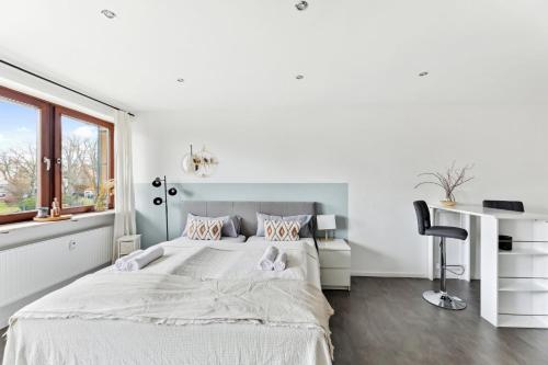 a white bedroom with a large bed and a desk at Salí Homes HZ42 Studio im Zentrum Bayreuths mit Balkon in Bayreuth