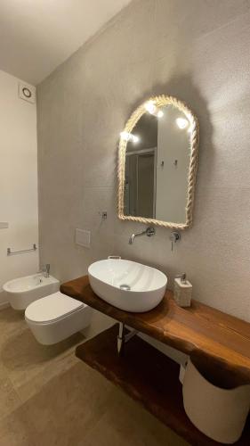 a bathroom with a sink and a toilet and a mirror at Cuore di Ognina - Appartamenti vista mare in Ognina