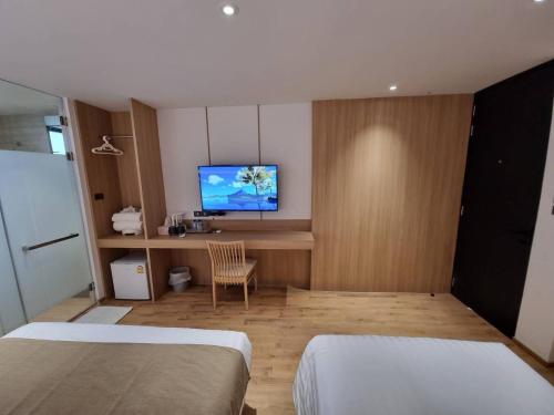 a bedroom with two beds and a desk with a tv at Nirundorn Resort Chaam in Cha Am