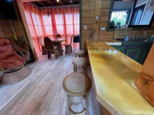 - une cuisine avec un bar et des tabourets dans une cabine dans l'établissement Parque Nacional Volcán Poás Cabaña Abby, à Bajos Tigre