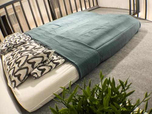 een bed met een groene deken op de vloer met een plant bij Nefelejcs apartman (Netflix) in Boedapest