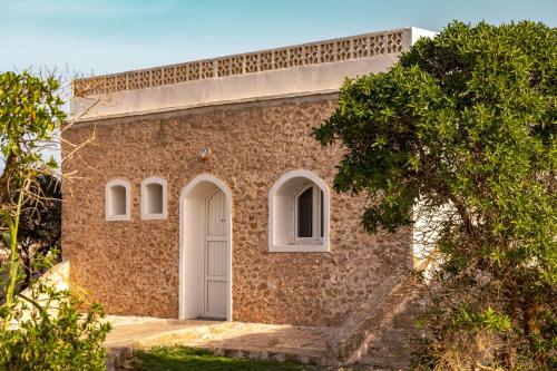 ein Backsteingebäude mit einer weißen Tür und einem Baum in der Unterkunft The Mogador's Oasis in Akermoud