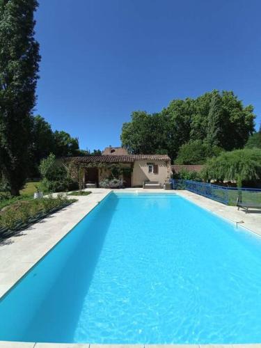 une grande piscine bleue devant une maison dans l'établissement Domaine de La Barde guest rooms and suites., au Bugue