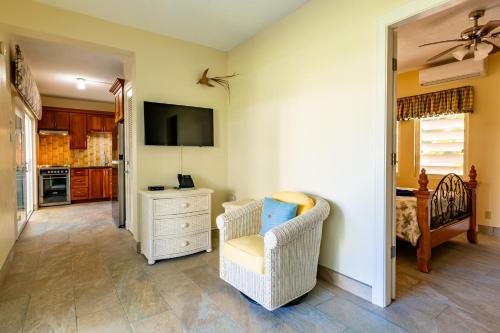 a living room with a chair and a television at Antigua Village Beach Resort in Saint Johnʼs