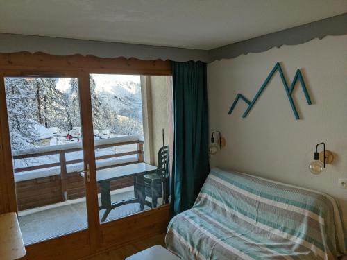 um quarto com uma cama e uma janela com vista para a montanha em Horizon Pelvoux Accueillant T2 pied des pistes em Puy-Saint-Vincent