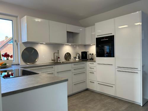 a white kitchen with white cabinets and appliances at Penthouse Jever - großzügige Dachterrasse in Jever