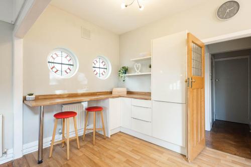 a kitchen with white cabinets and red bar stools at Spacious, Smart TV, Wi-fi, Balcony, Garden in Bristol