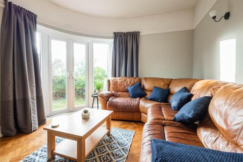 a living room with a brown leather couch and blue pillows at Spacious, Smart TV, Wi-fi, Balcony, Garden in Bristol