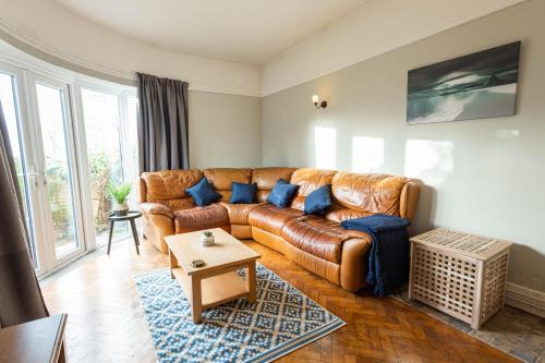 a living room with a brown leather couch and blue pillows at Spacious, Smart TV, Wi-fi, Balcony, Garden in Bristol