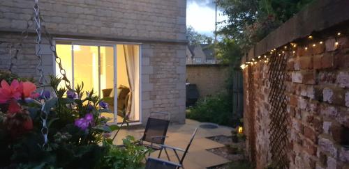 a patio with chairs and flowers and a brick wall at Meadow View in Stamford