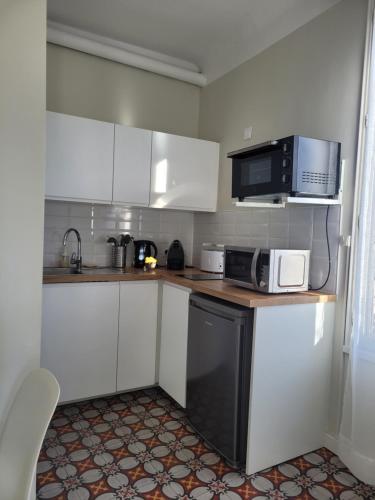 una pequeña cocina con armarios blancos y microondas en Studio Sommieres, en Sommières