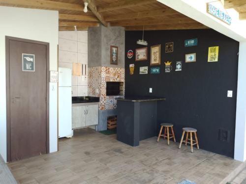 una cocina con 2 taburetes y una pared negra en Casa de férias temporada, en Xangri-lá