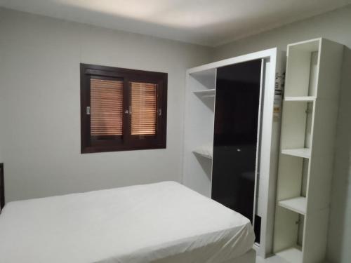 um quarto branco com uma cama e uma janela em Casa de férias temporada em Xangri-lá