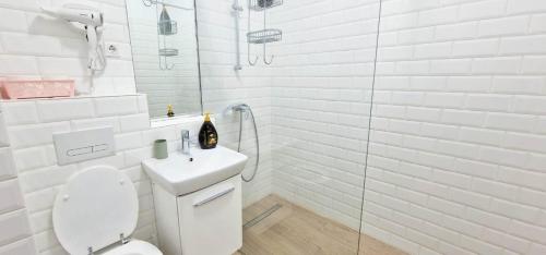 a white bathroom with a toilet and a sink at Designed like Home Apartment near Palas Mall in Iaşi