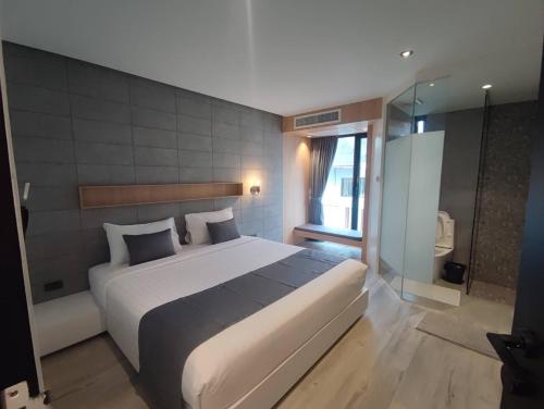 a bedroom with a large bed and a glass shower at Nirundorn Resort Chaam in Cha Am