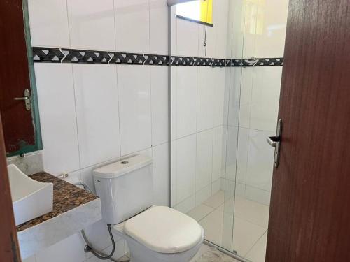 uma casa de banho com um WC e uma cabina de duche em vidro. em Apartamento mobiliado em Porto Seguro