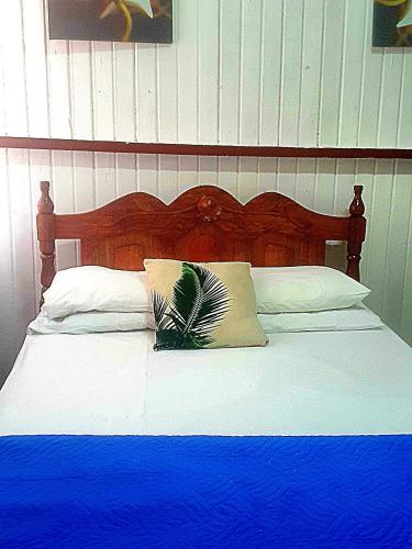 a bed with a wooden headboard with a blue blanket at SMITH'S BNB ROOMS in Georgetown