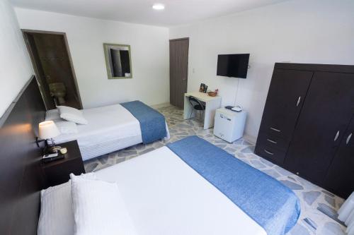 a hotel room with two beds and a television at Babilla Suites in Cali