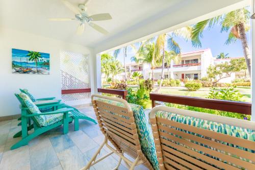 a porch with two chairs and a table and a view of the ocean at Antigua Village Beach Resort in Saint Johnʼs