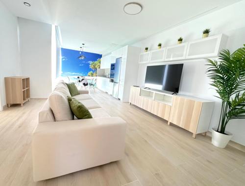 a white living room with a white couch and a tv at Suites Verano Azul in Castillo del Romeral