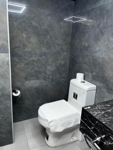 a bathroom with a white toilet and a black wall at Abu Sanaa Hotel in As Sulaymānīyah