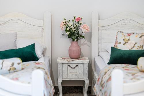 a bedroom with two beds and a vase with flowers on a night stand at Modra Sikorka in Smardzewice