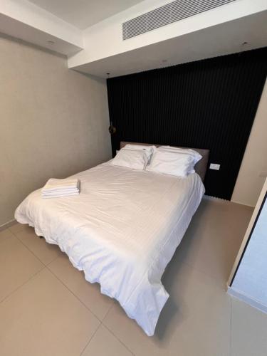 un letto con lenzuola e cuscini bianchi in una stanza di סויטה מול הים סיסייד a Eilat