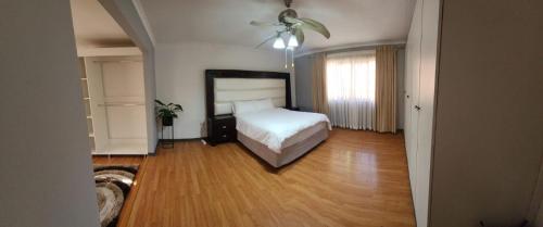 a bedroom with a white bed and a wooden floor at Jo's Eden in Edenvale