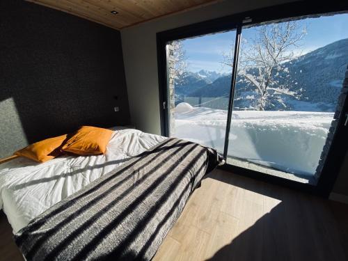 ein Schlafzimmer mit einem Bett und einem großen Fenster in der Unterkunft CHALET CONFIDENTIEL VALMOREL - Chalet de Haut de Gamme 4 étoiles 12 personnes in Doucy