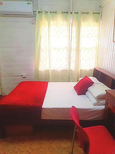 a bedroom with a bed and two red chairs at SMITH'S BNB ROOMS in Georgetown
