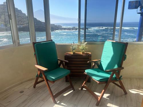 duas cadeiras verdes num quarto com vista para o oceano em The Waves em El Pris