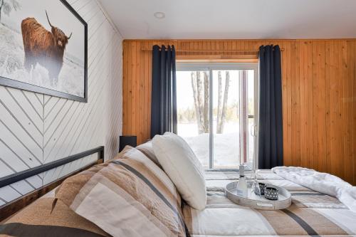 1 dormitorio con cama y ventana grande en Chalet bord de l'eau et sentier, en Mont-Laurier