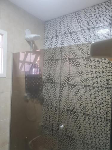 a bathroom with a shower with a tiled wall at Casa em Torres in Torres