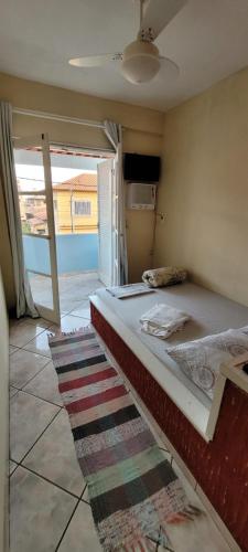 a bedroom with a bed and a window and a rug at Suítes Praia Do Foguete in Cabo Frio