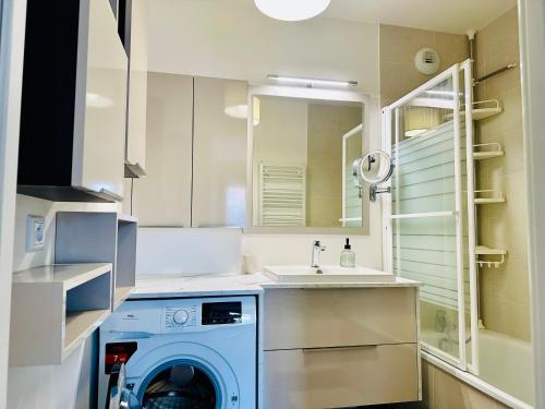 uma máquina de lavar e secar roupa numa cozinha com lavatório em T2 cosy- gare à pied- Disney-Paris- jardin privatif em Villenoy