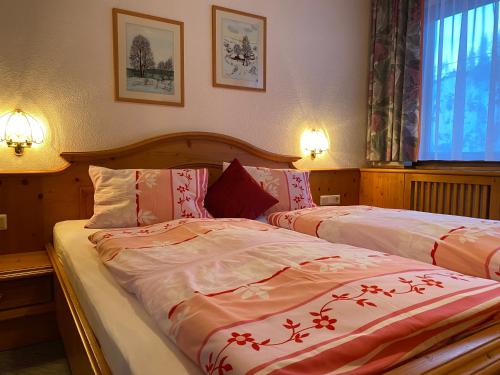 - une chambre avec 2 lits dotés de draps rouges et blancs dans l'établissement Haus Bergheim, à Ramsau am Dachstein