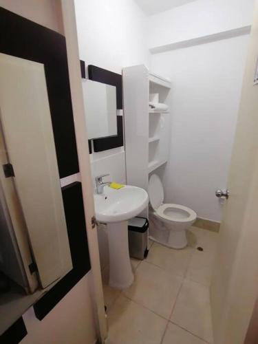 uma casa de banho com um WC branco e um lavatório. em Mini departamento lujo em Lima