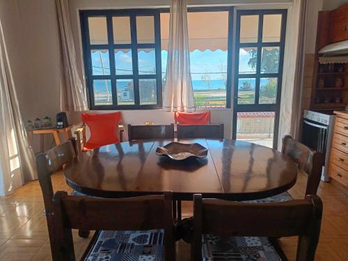 uma mesa de jantar com cadeiras e uma grande janela em Nafplion Seaside em Néa Kíos